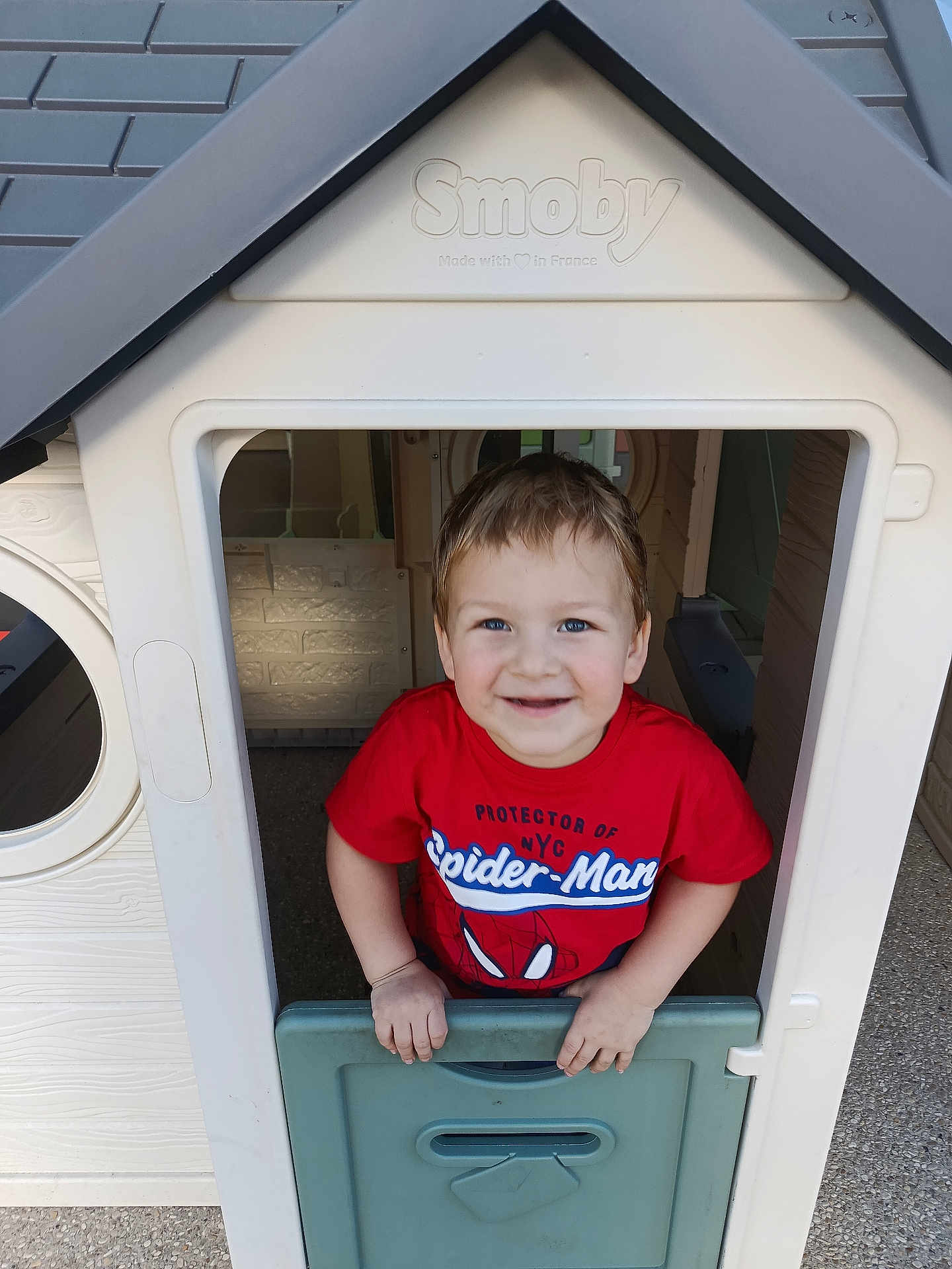 Gabriel participe au concours pour gagner de l'argent avec cette photo : child, boy, playhouse, toy_house, smiling, red_shirt, spiderman, blue_eyes, short_hair, outdoor, play, plastic, door, hand, happy, casual_clothing, young, cute, fun, portrait