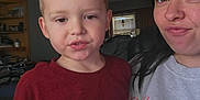 Rylan is registered to the contest to win money with this photo: child, woman, indoor, selfie, casual, maroon_shirt, gray_sweatshirt, face, portrait, people, home, window, blinds, shelf, furniture, expression, pout, smile, young_boy, family