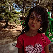 Ines participe au concours pour gagner de l'argent avec cette photo : child, girl, face_paint, red_shirt, heart_design, outdoor, trees, nature, playful, portrait, smile, daylight, hair, expression, park, young, casual_clothing, sunlight, green_equipment, background