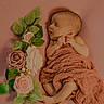 newborn, baby, sleeping, blanket, pink, flowers, roses, green_leaves, soft_texture, portrait, cute, infant, peaceful, wrapped, lying_down, delicate, skin, closeup, resting, cozy