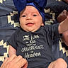 Avery is registered to the contest to win money with this photo: baby, infant, blue_bow, headband, onesie, smiling, happy, hand, child, blanket, patterned_blanket, text_on_clothing, navy_clothing, lying_down, indoor, cute, family, toddler, portrait, skin