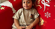 Manoa a rejoint le concours — aidez-le/la à gagner de superbes lots ! child, smiling, indoor, couch, christmas, festive, red, beige_clothing, relaxed, holiday, snowflakes, stars, young_child, face, casual, sitting, home, portrait, happy, decor
