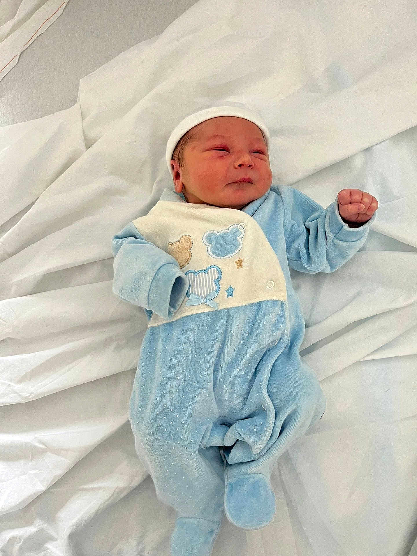 Adam participe au concours pour gagner de l'argent avec cette photo : newborn, baby, infant, blue_clothing, onesie, hat, sleeping, lying_down, white_sheet, cute, small_hands, face, peaceful, soft_texture, indoors, child, portrait, cozy, toddler, human