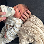 Adam a rejoint le concours — aidez-le/la à gagner de superbes lots ! baby, newborn, feeding, bottle, hand, blanket, couch, clothing, striped, person, infant, face, expression, soft, texture, comfort, toddler, indoor, care, nurture