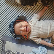 Aleks participe au concours pour gagner de l'argent avec cette photo : baby, child, smiling, hat, onesie, striped_blanket, lying_down, happy, infant, cute, face, headwear, baby_clothing, cheerful, young_child, relaxed, indoors, blanket, portrait, baby_toy