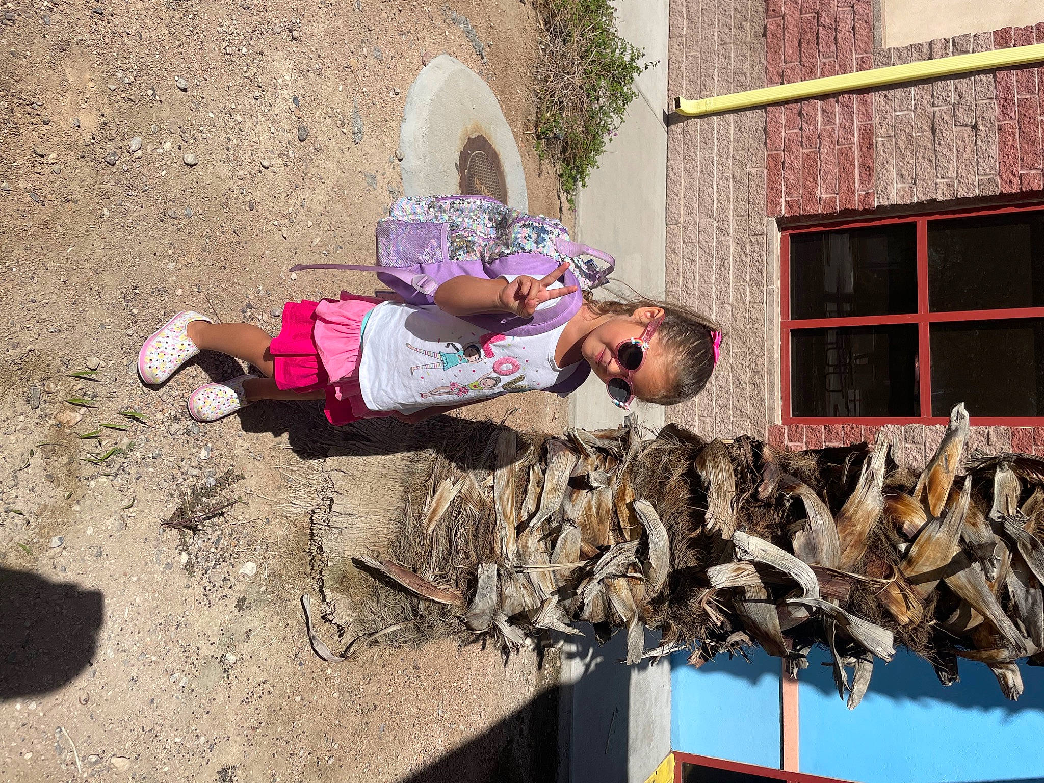 Aliya is registered to the contest to win money with this photo: concrete, eyewear, facade, fun, hat, leisure, person, plant, shadow, sitting, soil, sun_hat, toddler, tree, visual_arts, window, wood