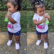 Jenesis is registered to the contest to win money with this photo: toddler, child, juice_box, outdoor, greenery, pavement, pink_shirt, navy_shorts, heart_pattern, pink_crocs, curly_hair, hair_clips, drinking, standing, casual_clothing, young_child, daylight, nature, playful, cute