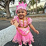 toddler, child, girl, princess_costume, pink_dress, crown, smile, outdoor, hand_holding, trees, fence, pavement, shoes, happy, person, costume, daylight, dress_up, gold_trim, playful