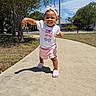 toddler, child, outdoor, sidewalk, sunny, blue_sky, trees, grass, pink_bow, white_tshirt, pink_shorts, pink_shoes, happy, smiling, walking, person, clothing, daylight, nature, portrait