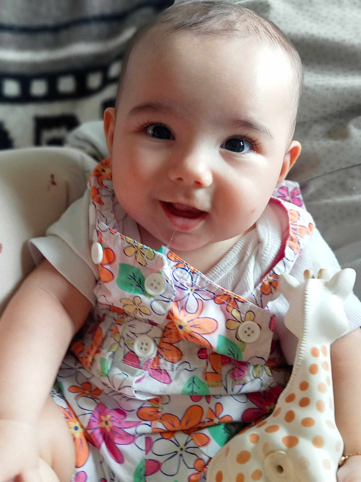 Alya participe au concours pour gagner de l'argent avec cette photo : baby, infant, smile, face, toy, giraffe, clothing, floral_pattern, buttons, arm, hand, blanket, fabric, person, cute, happy, child, indoor, closeup, portrait
