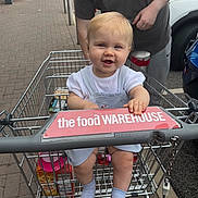 Lyla is registered to the contest to win money with this photo: adult, baby, car, child, clothing, daytime, grocery, hand, happy, outdoor, parking_lot, pavement, person, retail, shopping_cart, sign, smile, socks, store, transport