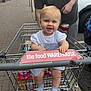 adult, baby, car, child, clothing, daytime, grocery, hand, happy, outdoor, parking_lot, pavement, person, retail, shopping_cart, sign, smile, socks, store, transport