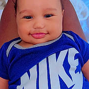 Edward joined the competition — help win amazing prizes! baby, smiling, blue_shirt, nike_logo, person, face, infant, clothing, portrait, indoor, legs, resting, happy, cute, head, child, young, skin, sitting, room
