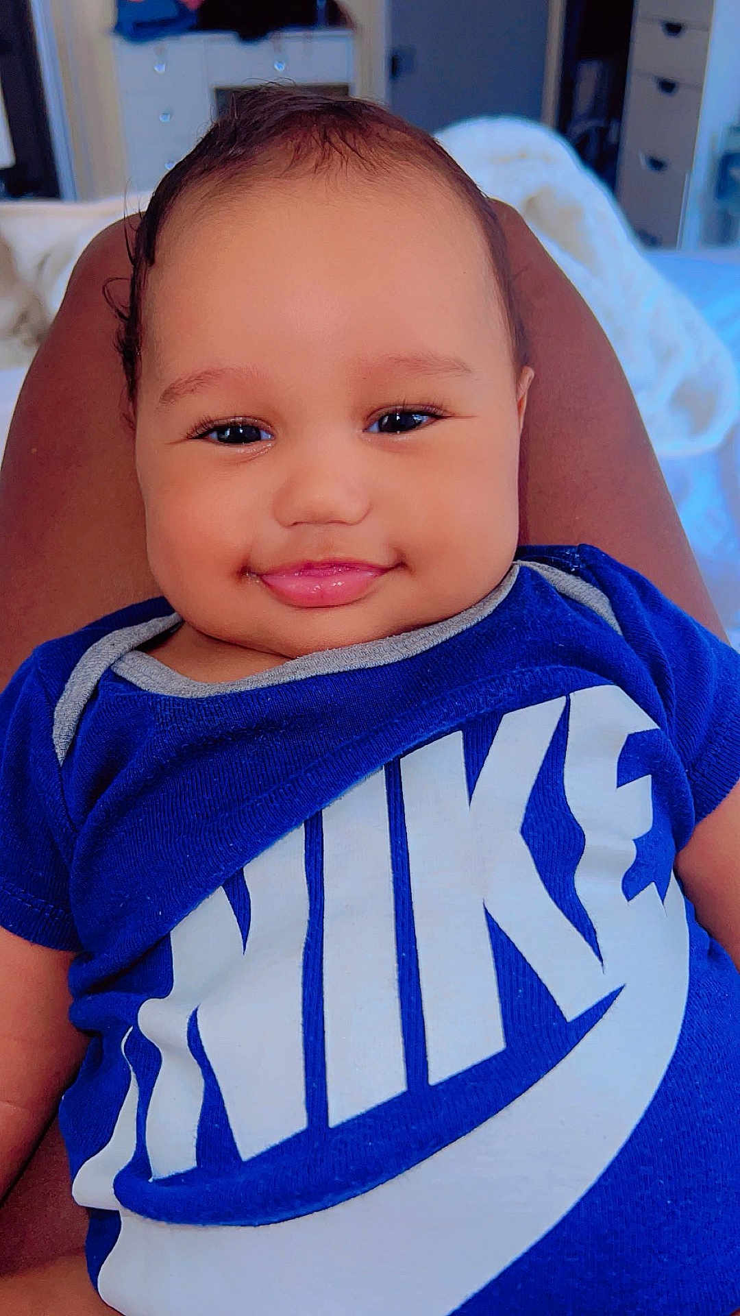 Edward joined the competition — help win amazing prizes! baby, smiling, blue_shirt, nike_logo, person, face, infant, clothing, portrait, indoor, legs, resting, happy, cute, head, child, young, skin, sitting, room