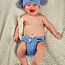 baby, infant, child, smiling, laughing, portrait, lying_down, knitted_hat, dog_hat, blue_clothing, diaper_cover, blanket, cozy, indoor, happy, playful, crocheted_toy, barefoot, close_up, adorable