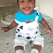 Malachi is registered to the contest to win money with this photo: baby, child, smiling, happy, infant, dinosaur_pattern, overalls, blue_shirt, socks, kitchen_counter, marble_surface, cute, portrait, indoor, person, young_child, joyful, sitting, face, expression