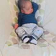 Rio is registered to the contest to win money with this photo: baby, newborn, sleeping, infant_seat, bedding, cushion, patterned_fabric, onesie, socks, small_hand, cheeks, head, portrait, cozy, nursery, resting, peaceful, soft_lighting, indoor, cute