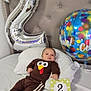baby, infant, bed, pillow, balloon, number_balloon, celebration, clothing, turkey_design, card, 2_months, headboard, white_bedspread, lying_down, smiling, cute, indoor, portrait, child, holiday