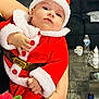 Nathan joined the competition — help win amazing prizes! baby, child, santa_claus_outfit, red_clothing, white_fur_trim, person, indoor, living_room, sofa, coffee_table, remote_control, water_bottle, cup, hand, carpet, holiday, festive, cute, portrait, holding