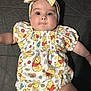 baby, infant, child, winnie_the_pooh, headband, clothing, cute, smiling, lying_down, patterned_outfit, face, skin, eyes, mouth, arm, hand, fabric, flower_pattern, red, yellow