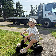 Colin joined the competition — help win amazing prizes! toddler, child, tricycle, hat, outdoor, grass, sidewalk, truck, tree, sunlight, footwear, play, vehicle, person, summer, nature, daytime, casual, transportation, expression
