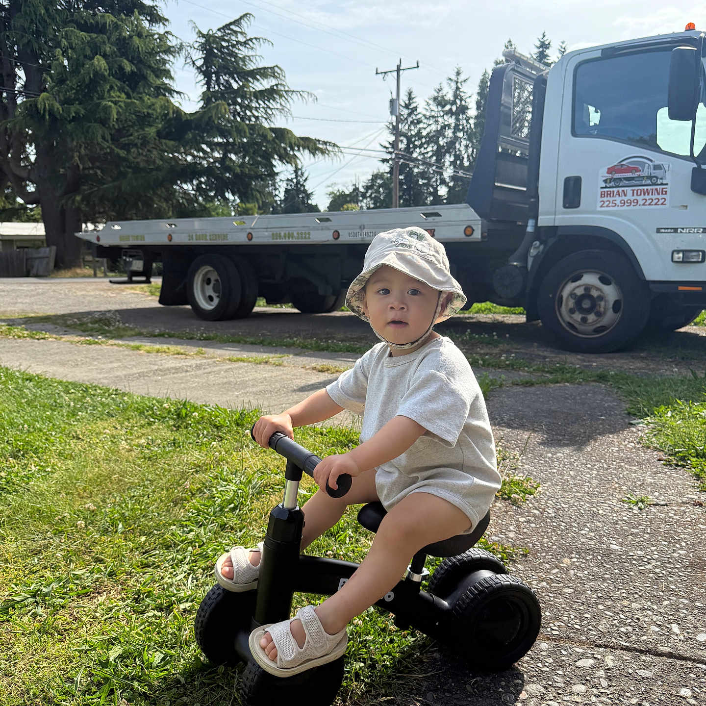 Colin joined the competition — help win amazing prizes! casual, child, daytime, expression, footwear, grass, hat, nature, outdoor, person, play, sidewalk, summer, sunlight, toddler, transportation, tree, tricycle, truck, vehicle