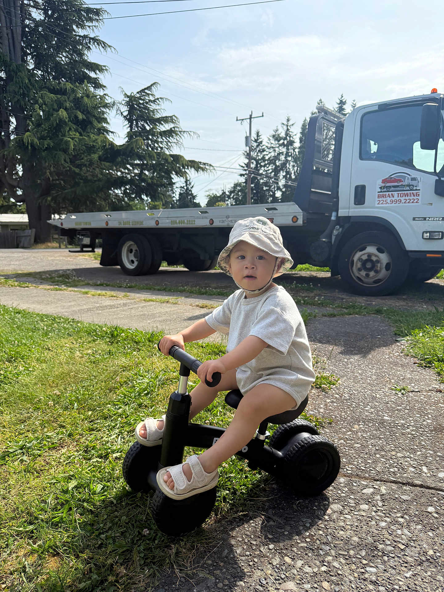 Colin joined the competition — help win amazing prizes! toddler, child, tricycle, hat, outdoor, grass, sidewalk, truck, tree, sunlight, footwear, play, vehicle, person, summer, nature, daytime, casual, transportation, expression