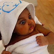 Keyssie Kaely a rejoint le concours — aidez-le/la à gagner de superbes lots ! baby, towel, hood, wrapped, curious, indoor, skin, hand, infant, child, cute, soft, expression, portrait, young, newborn, brown_skin, person, sitting, warm