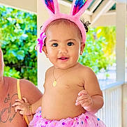 Isidora a rejoint le concours — aidez-le/la à gagner de superbes lots ! child, baby, toddler, bunny_ears, pink_tutu, flower_hairclip, necklace, earrings, smile, portrait, outdoor, greenery, sunlit, adult_arm, tattoo, playful, bright_colors, railing, cute, fashion_costume