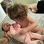 Hazel is registered to the contest to win money with this photo: baby, child, curly_hair, pajamas, bed, couch, tattoo, person, indoor, family, holding, infant, sleepwear, smile, skin, legs, hand, home, blanket, toddler