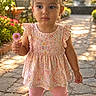 child, toddler, girl, portrait, garden, outdoor, flower, daisy, dress, floral_dress, pink, leggings, shoes, pigtails, hair_bows, standing, pathway, sunlight, fountain, smiling