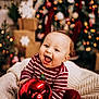 baby, child, christmas, holiday, ornament, red, striped_clothing, smiling, happy, indoors, decorations, tree, lights, blanket, festive, cute, cozy, celebration, toddler, joy
