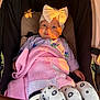 Maeve is registered to the contest to win money with this photo: baby, blanket, bow, child, clothing, face, hand, headwear, infant, knitted, outdoor, person, portrait, pram, seat, smile, stroller, sunlight, toddler, warm_light