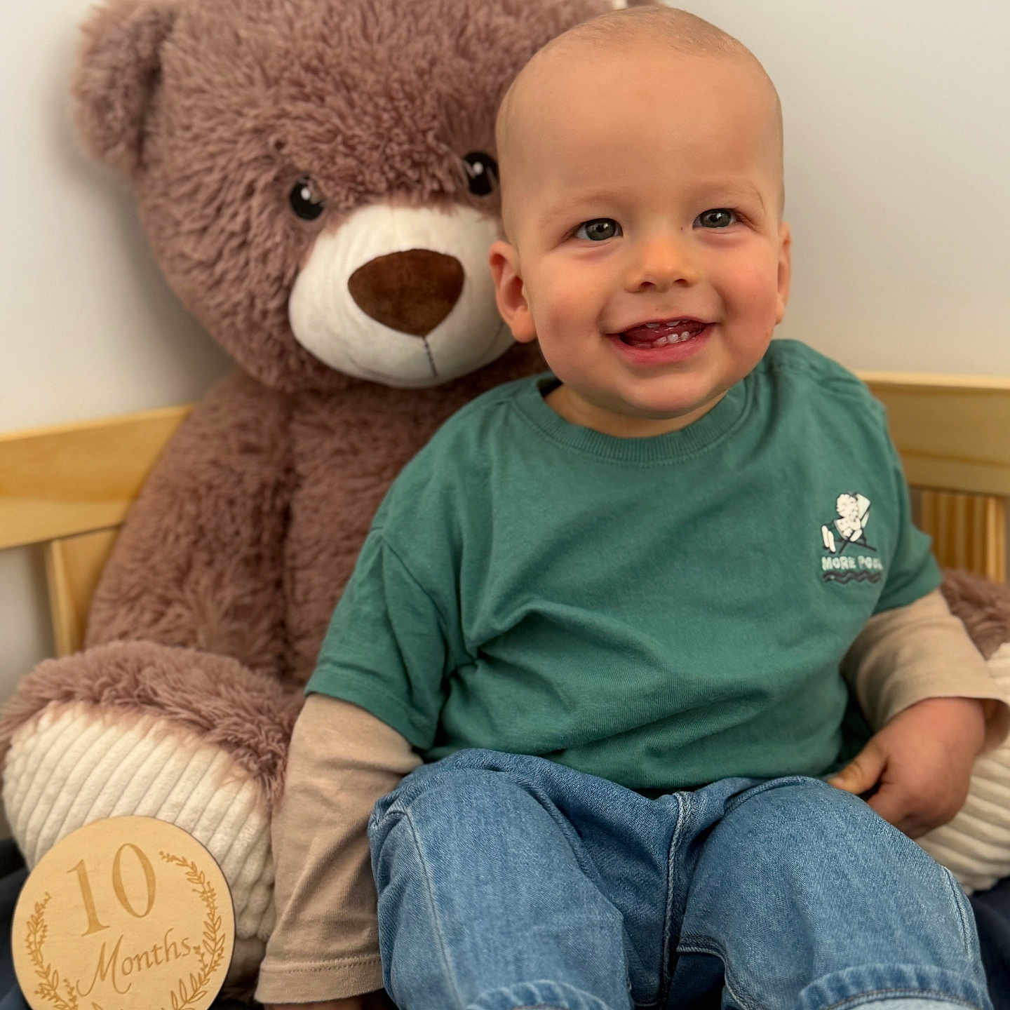Rafaël a rejoint le concours — aidez-le/la à gagner de superbes lots ! 10_months, baby, cheeks, child, cozy, crib, green_shirt, happy, indoor, jeans, milestone_disc, nursery, plush_toy, portrait, sitting, smiling_child, teddy_bear, teeth, toddler, wooden_plaque
