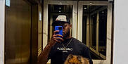 Lambo is registered to the contest to win money with this photo: man, dog, pom, mirror, selfie, elevator, gold, marble, cap, tshirt, phone, reflection, smile, pet, indoor, casual, portrait, holding, happy, lighting