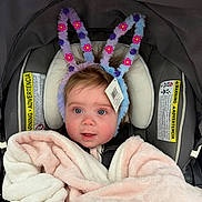 Lola joined the competition — help win amazing prizes! baby, infant, child, car_seat, blanket, headband, fuzzy_antennae, flower_decor, price_tag, pink, purple, plush, face, eyes, smile, blanket_wrapped, safety_label, canopy, seatbelt, portrait