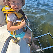 Maylonn a rejoint le concours — aidez-le/la à gagner de superbes lots ! blue_shorts, boat, child, happy, hat, lake, life_jacket, metal_rail, nature, outdoor, person, recreation, smiling, splashing, summer, sunlight, sunny_day, vacation, water, water_sports