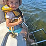 blue_shorts, boat, child, happy, hat, lake, life_jacket, metal_rail, nature, outdoor, person, recreation, smiling, splashing, summer, sunlight, sunny_day, vacation, water, water_sports