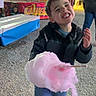 amusement_park, carnival, child, clothing, cotton_candy, fair, festival, food, fun, gravel_ground, happy, jacket, lights, night, outdoor, people, person, smiling, sneakers, sweet