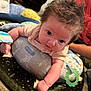 Gracelynn is registered to the contest to win money with this photo: baby, infant, pillow, blanket, toy, indoor, curly_hair, looking_at_camera, toddler, child, cute, playtime, cushion, person, floor, cozy, colorful, expression, lying_down, soft