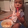Jeremiah is registered to the contest to win money with this photo: toddler, child, spoon, bowl, food, eating, bib, chair, indoor, kitchen, fan, floor, person, mealtime, home, furniture, clothing, face, hand, expression