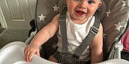 Thomas joined the competition — help win amazing prizes! baby, child, high_chair, smiling, happy, blue_eyes, white_tank_top, straps, indoor, door, carpet, plastic_tray, star_pattern, seat, furniture, person, cute, infant, portrait, hand