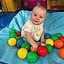 Thomas is registered to the contest to win money with this photo: baby, child, smiling, blue_mat, colorful_balls, playroom, indoor, cushioned_furniture, happy, cute, infant, sitting, toy, play, person, young_child, bright_colors, soft_surface, cheerful, curious