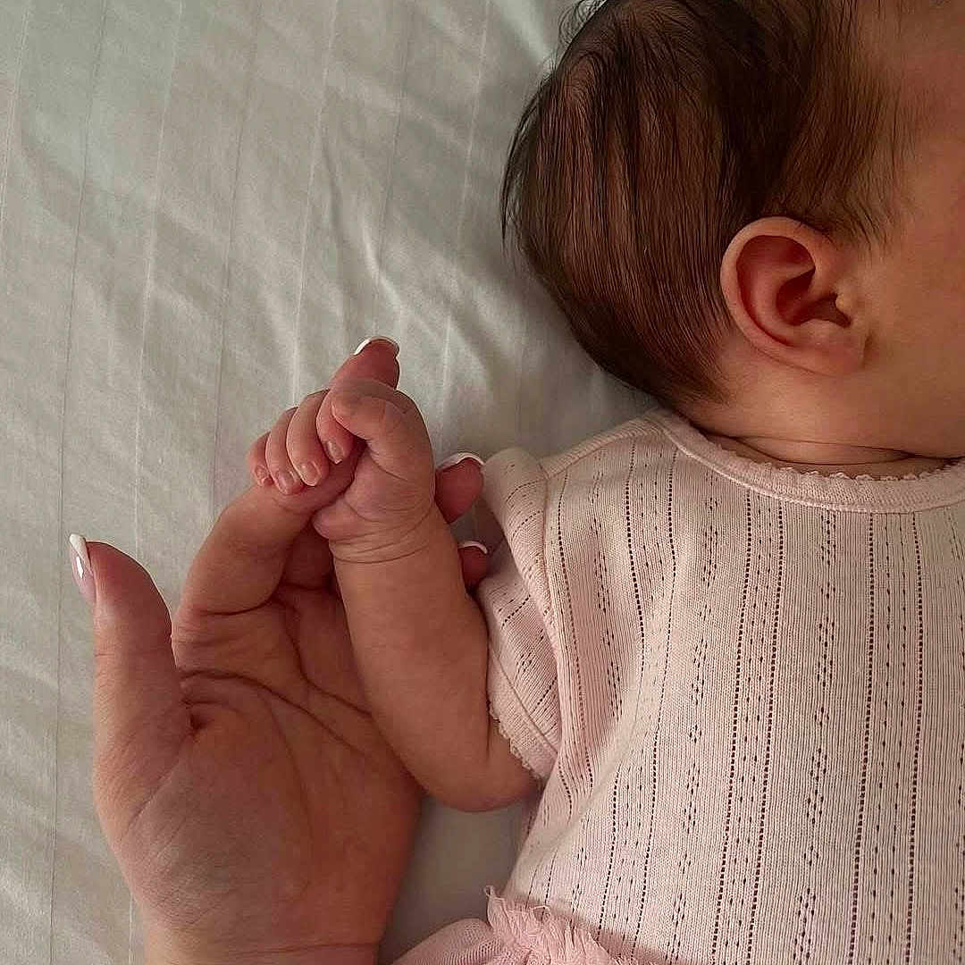 Sarra participe au concours pour gagner de l'argent avec cette photo : adult_hand, baby, baby_girl, bed_sheet, close_up, comfort, cute, fingernails, hand, holding, human_connection, infant, newborn, pink_clothing, resting, skin, sleeping, small, soft_light, tender