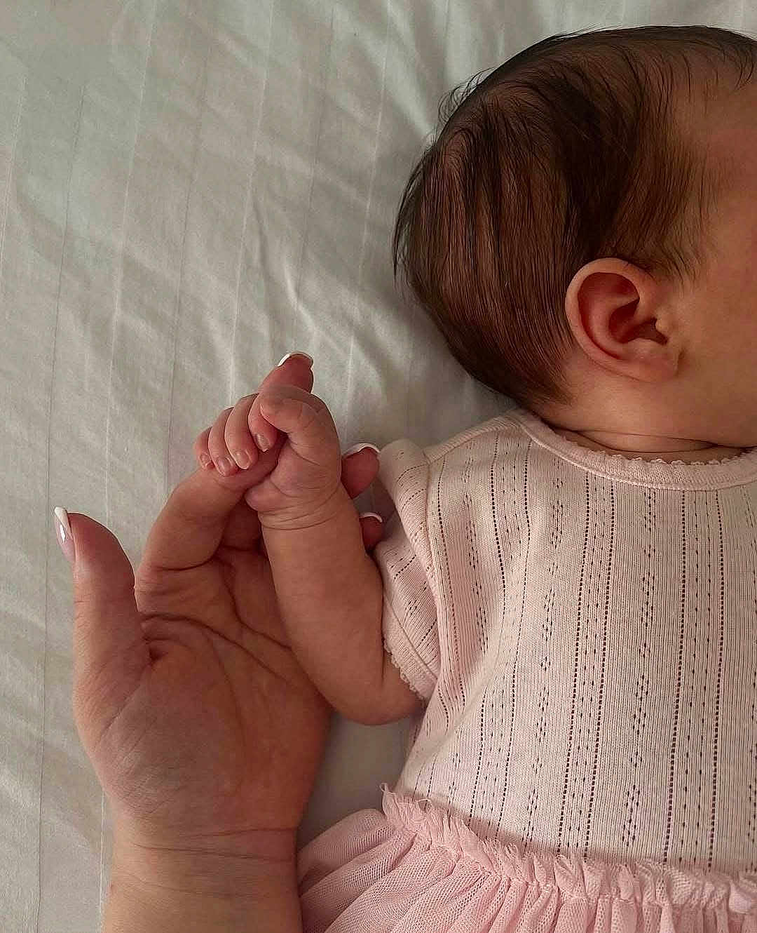 Sarra participe au concours pour gagner de l'argent avec cette photo : baby, infant, hand, adult_hand, holding, skin, pink_clothing, bed_sheet, close_up, newborn, fingernails, soft_light, human_connection, cute, small, tender, sleeping, baby_girl, resting, comfort