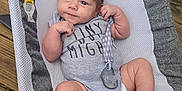 Hendrix joined the competition — help win amazing prizes! baby, baby_accessories, baby_seat, clothing, cute, expression, face, feet, gray, hair, hands, infant, infant_toys, onesie, outdoor, pacifier, person, sitting, white, wooden_deck