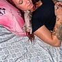 woman, kitten, sleeping, bed, pillow, mickey_mouse, tattoo, black_shirt, red_hair, resting, patterned_bedspread, indoor, pet, animal, cute, cozy, closeup, relaxation, human, sleep
