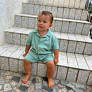 Manua a rejoint le concours — aidez-le/la à gagner de superbes lots ! toddler, child, steps, tile, barefoot, outdoor, curious, green_clothing, mosaic_floor, sitting, person, young_child, texture, pattern, casual, daylight, concrete, wall, portrait, expression