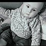 arm, baby, casual_clothing, child, closeup, cute, denim_pants, eyes, face, hands, indoor, infant, knitted_sweater, monochrome, person, portrait, relaxed, seated, soft_lighting, tattoo