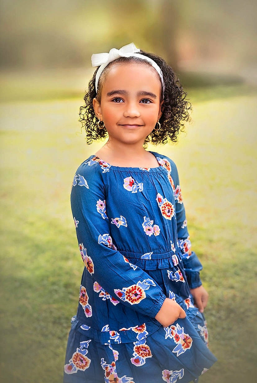 Damaris is registered to the contest to win money with this photo: baby_toddler_clothing, black_hair, day_dress, dress, electric_blue, face, flash_photography, fun, grass, grassland, hair, happy, joy, one_piece_garment, pattern, people_in_nature, person, plant, sleeve, smile